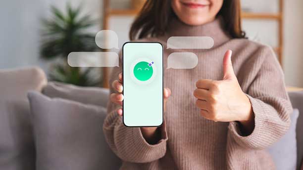 Senhora segura smartphone, onde se vê o símbolo do assistente vistual da DECO PROteste, o Ollie